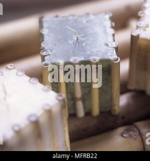 Square blue candles with bamboo edging on a bamboo table. Stock Photo