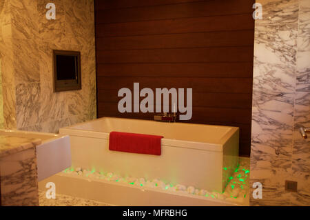 Angular bathroom with marble floor and modern lighting underneath bath Stock Photo