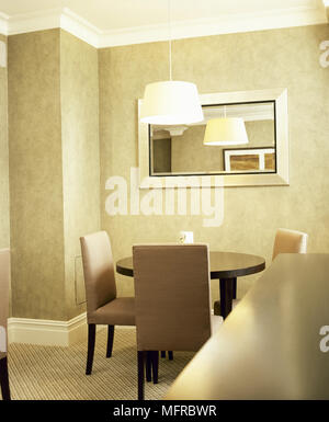 Modern dining room with a round dining table and upholstered chairs, carpeted floor, and hanging lamp. Stock Photo