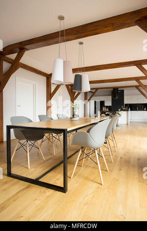 Side angle of wooden dining table with grey chairs set in spacious room interior Stock Photo