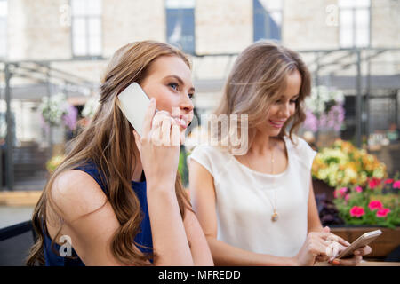 young women with smartphones and coffee at cafe Stock Photo