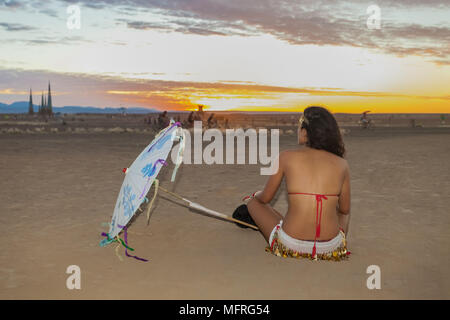 Young girl watching a desert sunset at outdoor festival Stock Photo