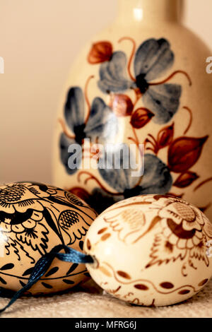 Two brown Easter eggs  with  a large brown vase. Two  hand-painted Czech Easter eggs rest beside a large brown jug. The eggs are  hand painted with tr Stock Photo