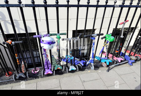 London, England, UK. Children's scooters chained to railings outside a central London primary school Stock Photo