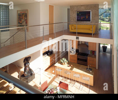 A modern open plan living space with kitchen and dining area upper floor level with steel railings