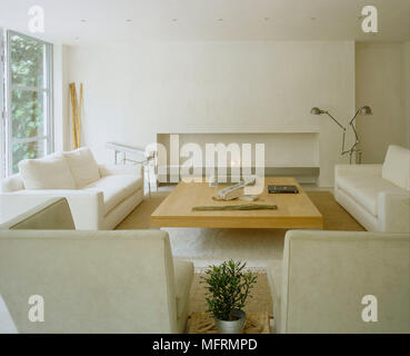 A Modern Neutral Sitting Room With Upholstered Sofas Armchairs Wood Coffee Table And Simple Shelf Fireplace Stock Photo Alamy