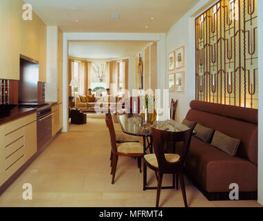 A modern kitchen diner with glass table banquette seating and chairs open doorway to sitting room Stock Photo