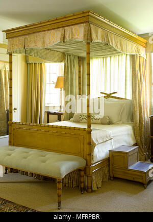 Wooden four poster with bed canopy in traditional style bedroom Stock Photo