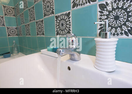 Porcelain wash basin with soap holder and decorative tiled wall Stock Photo