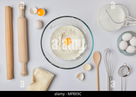 top view of glass bowl with flour and egg on tabletop Stock Photo