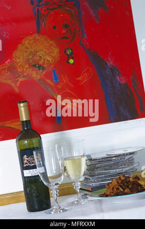Bottle of white wine and two wine glasses, one filled with wine and plate of food Stock Photo