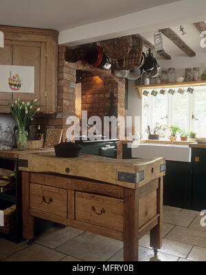 Wooden drawer unit with an old fashioned butchers block on top in country style room Stock Photo