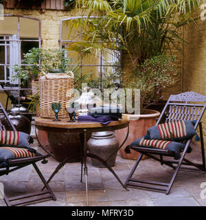 A courtyard garden with a paved patio area wood table chairs plants in pots Stock Photo
