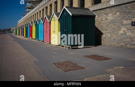 A line of multi coloured colourful locked and empty beach huts at Boscombe part of Bournemouth beach in Dorset England. Stock Photo