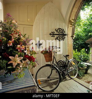 Bicycle leaning against open gothic style front door into country hallway Stock Photo