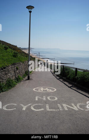 No cycling warning on footpath leading to Southbourne beach in Bournemouth with cyclist riding on. Stock Photo