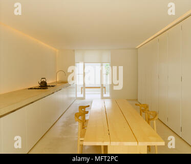 A modern, neutral minimalist  kitchen diner with simple wood table and chairs, stone work top on units Stock Photo