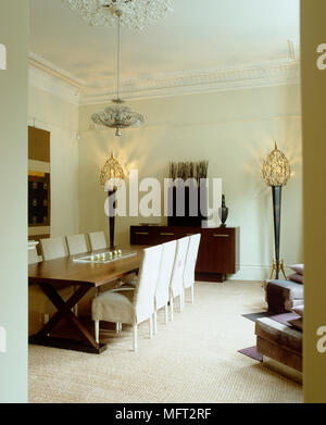 Fabric covered chairs at long wooden table in contemporary dining room Stock Photo
