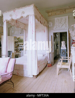 A traditional bedroom an 18th century four poster bed with fabric canopy and curtains stripped floorboards Stock Photo