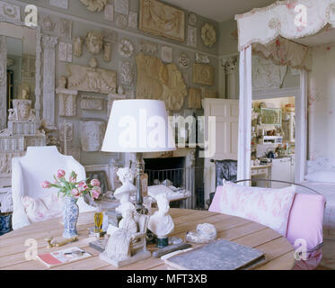 A traditional bedroom an 18th century four poster bed with fabric canopy a wood table display of plaster artifacts on the wall Stock Photo