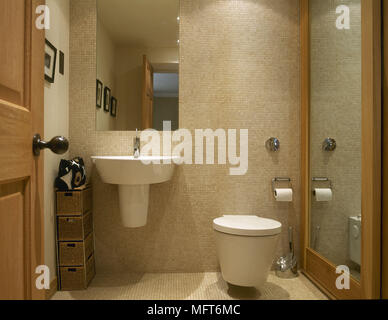 Wall mounted washbasin next to toilet in tiled bathroom Stock Photo