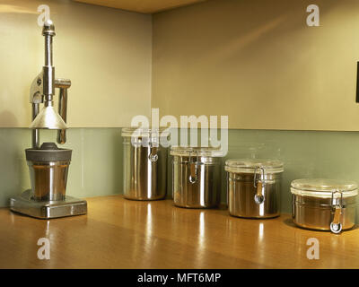Chrome storage jars and juicer on wooden worktop Stock Photo