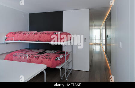 Metal bunk beds with red covers in minimalist bedroom with sliding doors Stock Photo