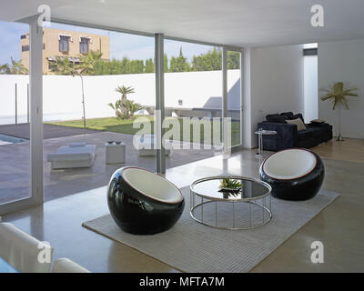 Pair of black chairs either side of metal table in modern minimalist room Stock Photo