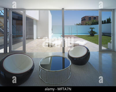 Pair of black chairs either side of metal table in modern minimalist room Stock Photo