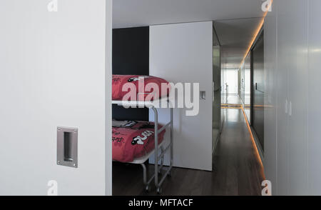 View through open sliding door to metal bunk beds with red covers Stock Photo