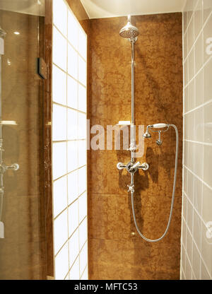 Modern bathroom detail of a shower stall with tile walls and a glass block window. Stock Photo