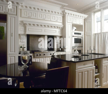 Traditional kitchen with white painted decorative moulding, black marble countertops, and a central island with breakfast bar. Stock Photo