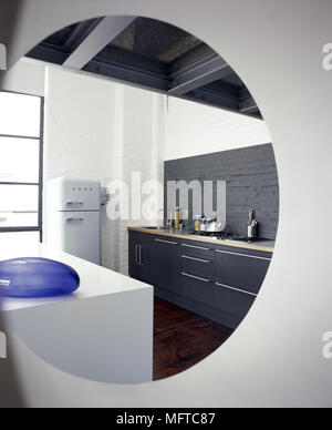 Modern kitchen with black painted brick wall, beamed ceiling, and vintage fridge viewed through a port hole. Stock Photo