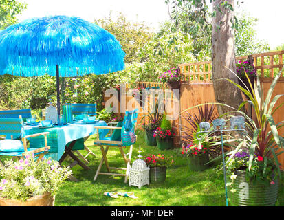 Table and chairs under parasol in garden Stock Photo