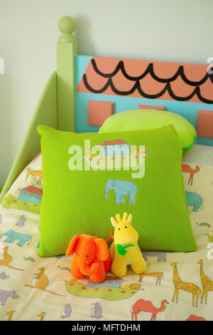 Cushion and soft toys on childs bed Stock Photo