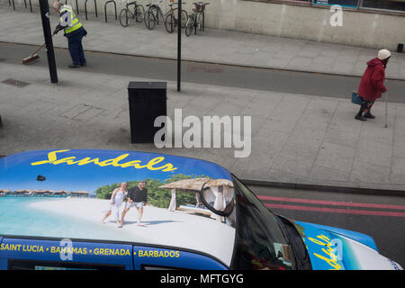 Aerial view of a Sandals Holidays ad on the roof of a London taxi and the reality of passers-by at Elephant & Castle on 23rd April 2018, in London, England. Stock Photo