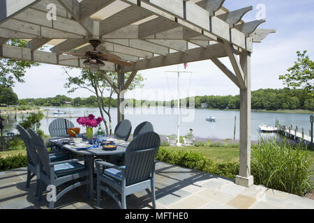 Table and chairs on patio overlooking lake Stock Photo