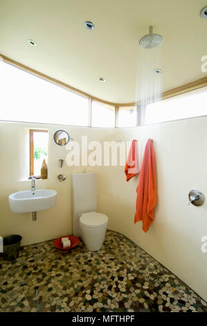 Wall mounted washbasin next to toilet and shower in wet room Stock Photo