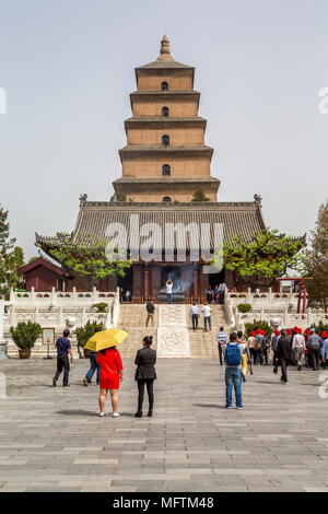 Tourists visit the Giant Wild Goose Pagoda, Xi'an, China. In front of the pagoda a worshipper raises an incense stick and the smoke blows in the wind. Stock Photo