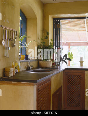Kitchen detail of work tops and cabinets with sink and kitchen tools hanging on wall Stock Photo