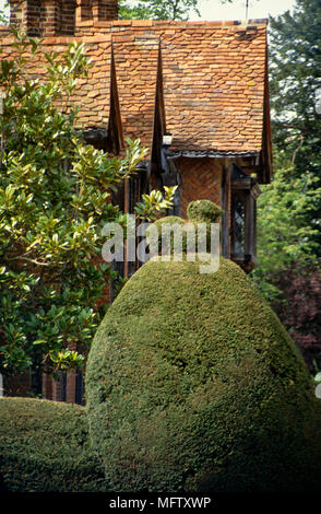 Topiary shrubs in garden with exterior of Dorney Country manor house in the background Stock Photo