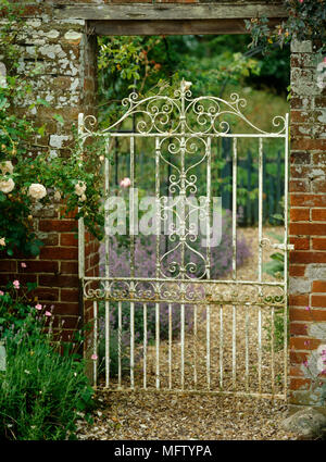 White painted metal garden gate in brick wall Stock Photo