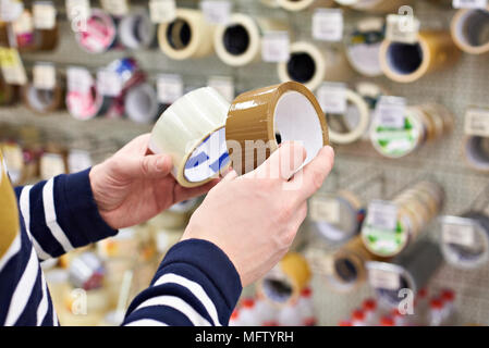 Man buyer chooses the adhesive duct tape in the store Stock Photo