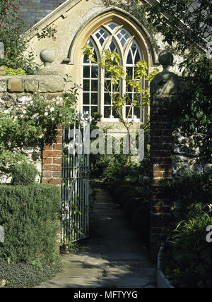 Wrought iron gate open leading to country style house with arched window Stock Photo