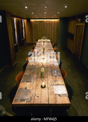 Dining room with long wooden table set for dinner. Stock Photo