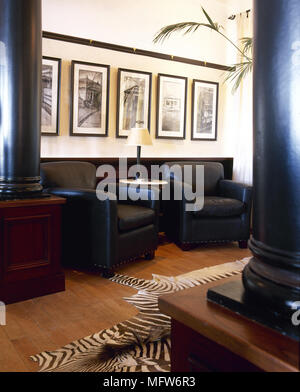 Traditional sitting room with columns, leather armchairs, framed prints, and an animal skin rug. Stock Photo