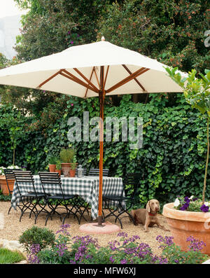 Patio area with table and chairs beneath parasol Stock Photo