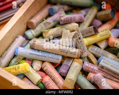 A close up photograph of a box of colorful used chalk pastels