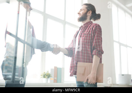 Two businessmen standing and shaking hands at office Stock Photo