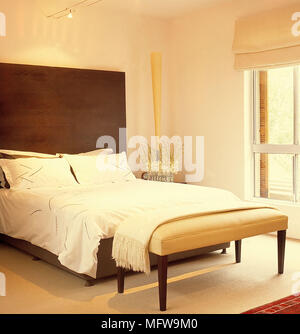 Upholstered ottoman at the foot of double bed Stock Photo